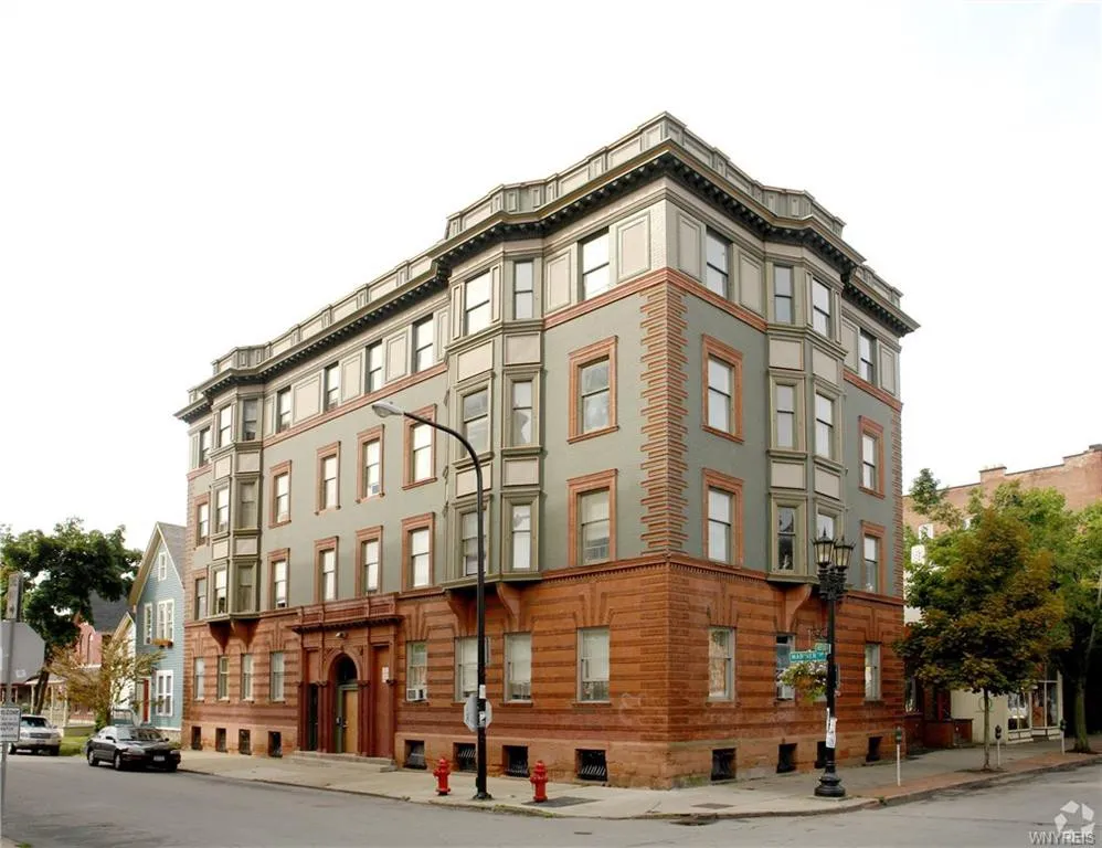 Historic corner apartment building in Buffalo, with green upper floors and a red masonry base